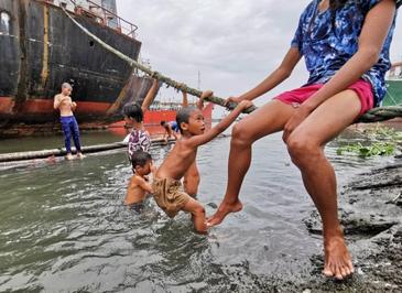 کودکان فیلیپینی در حال بازی در کنار کشتی‌ها در بندری در مانیل